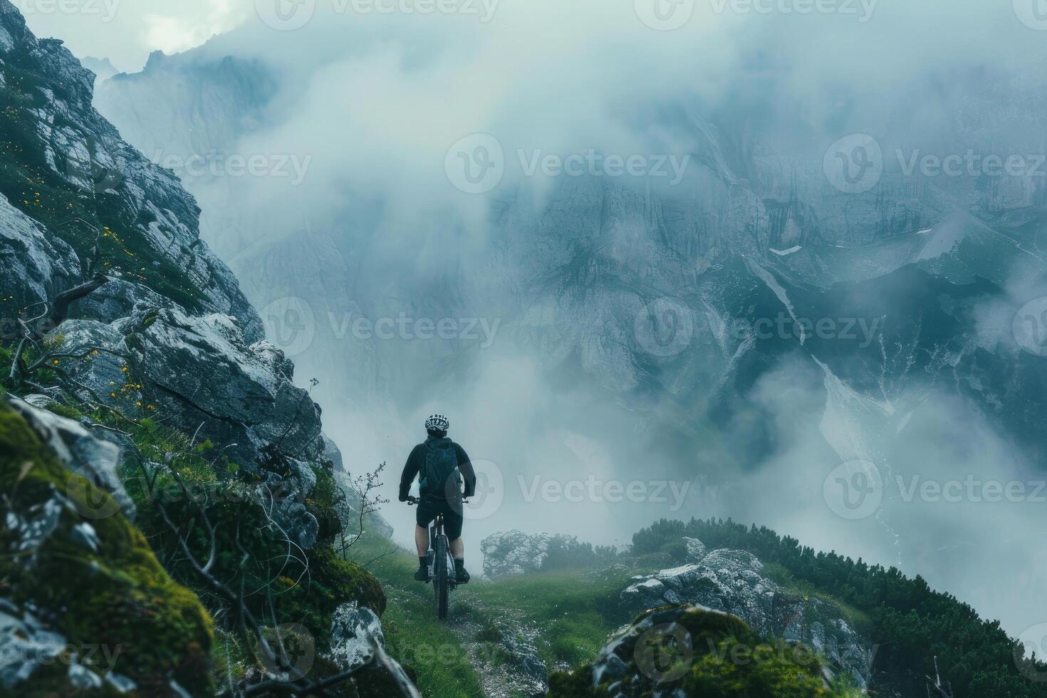 Mountain biker riding through the clouds on a mountain ridge trail photo