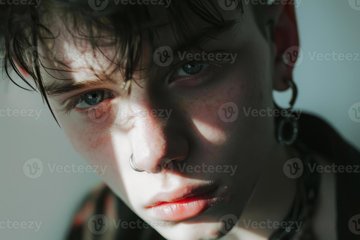 Portrait of a young man with piercings and wet hair posing in the sun photo