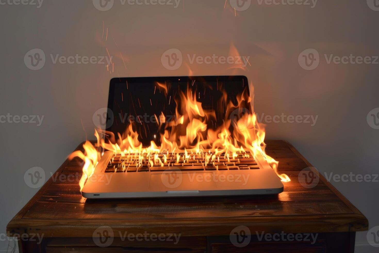 Laptop computer burning with flames on desk photo