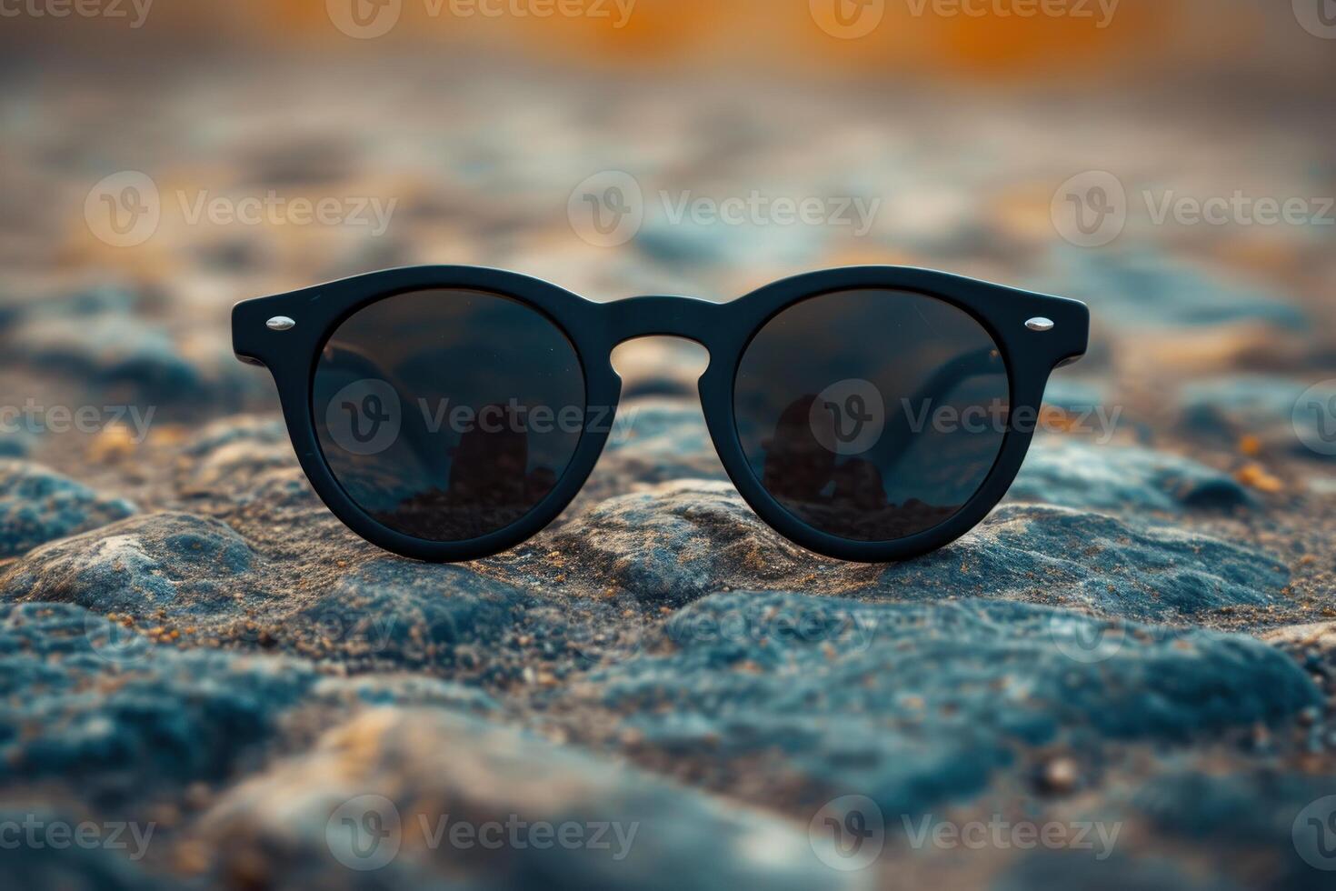Black sunglasses on rocky surface at sunset photo