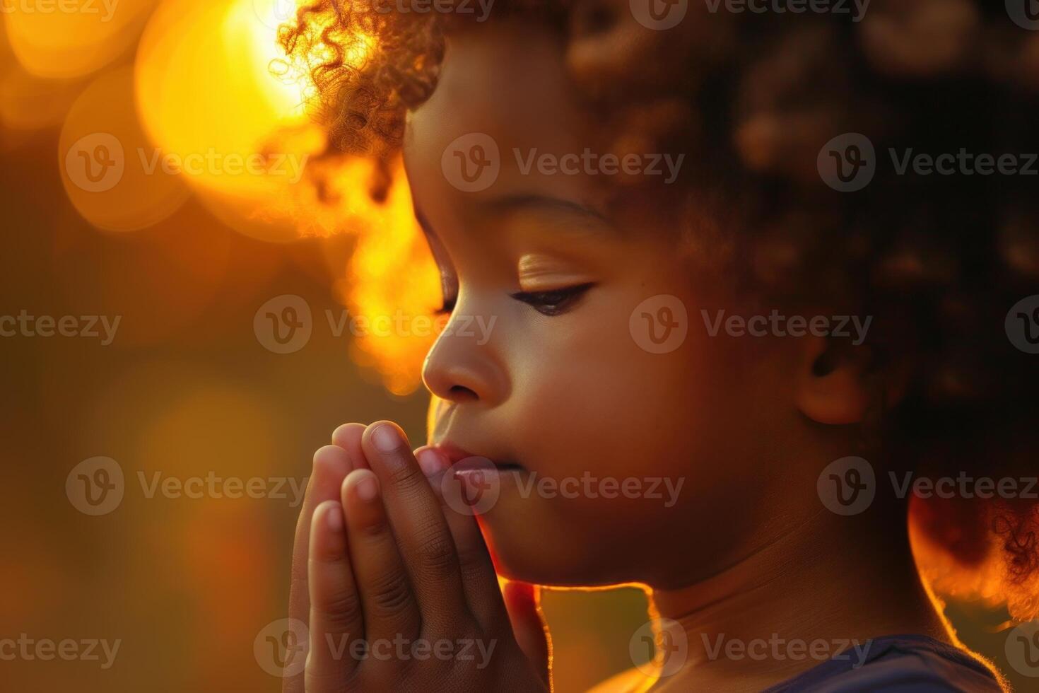 Serene young child with eyes closed, praying in golden sunset light photo