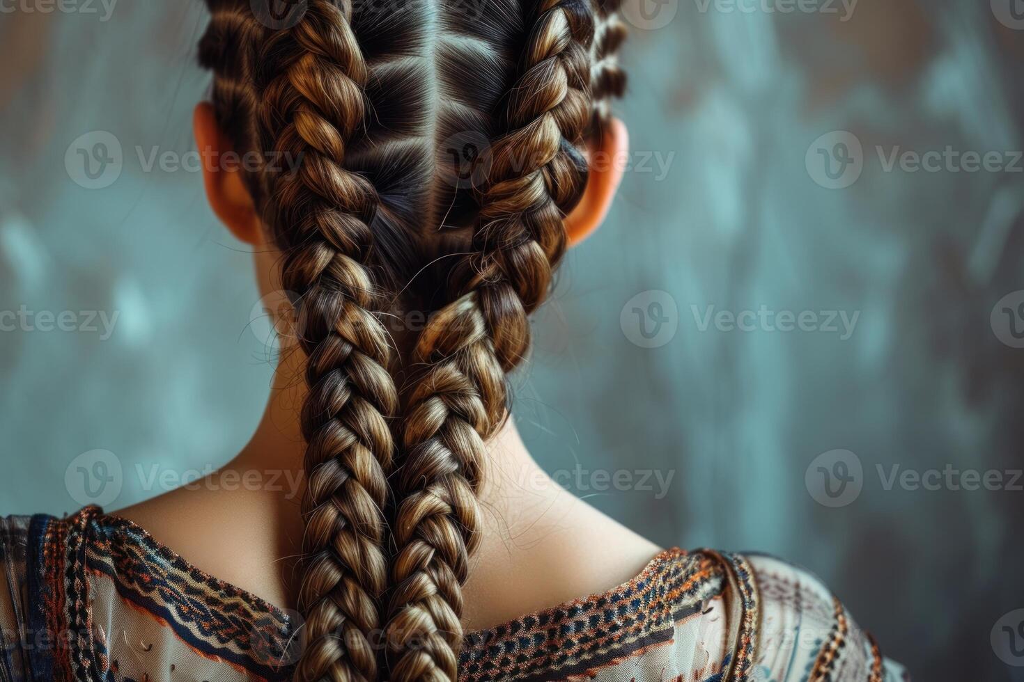 Close-up of a woman's back showcasing complex double braids against a soft-focus background photo