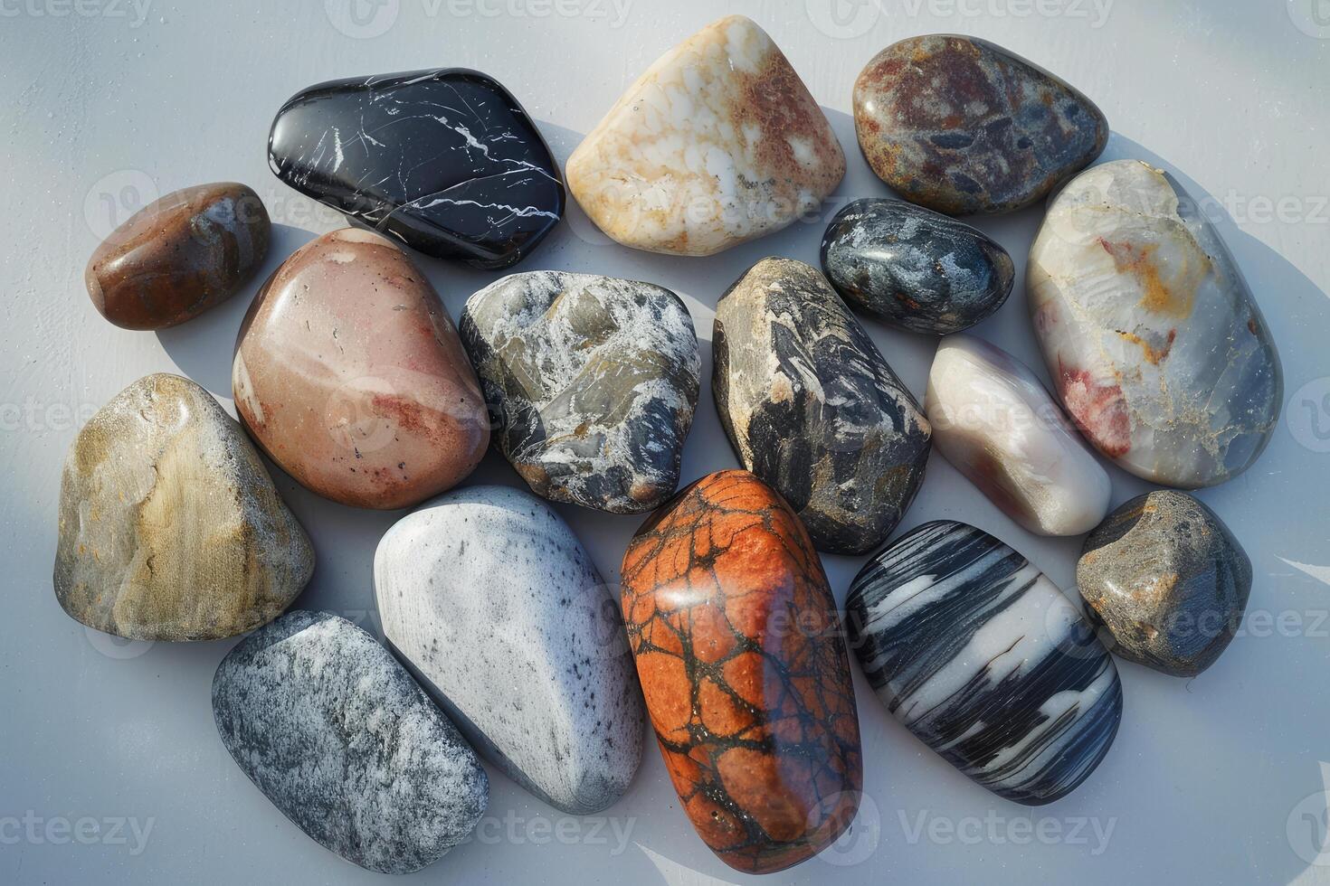 Variety of colorful polished rocks and minerals arranged neatly on a light surface photo
