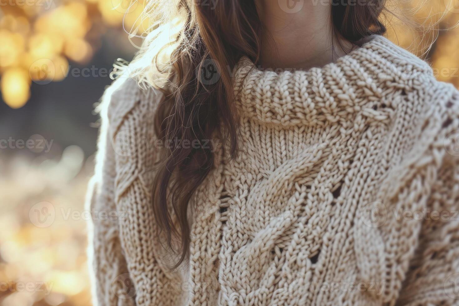 Close-up of a woman in a chunky knit sweater during fall, with a golden backdrop photo