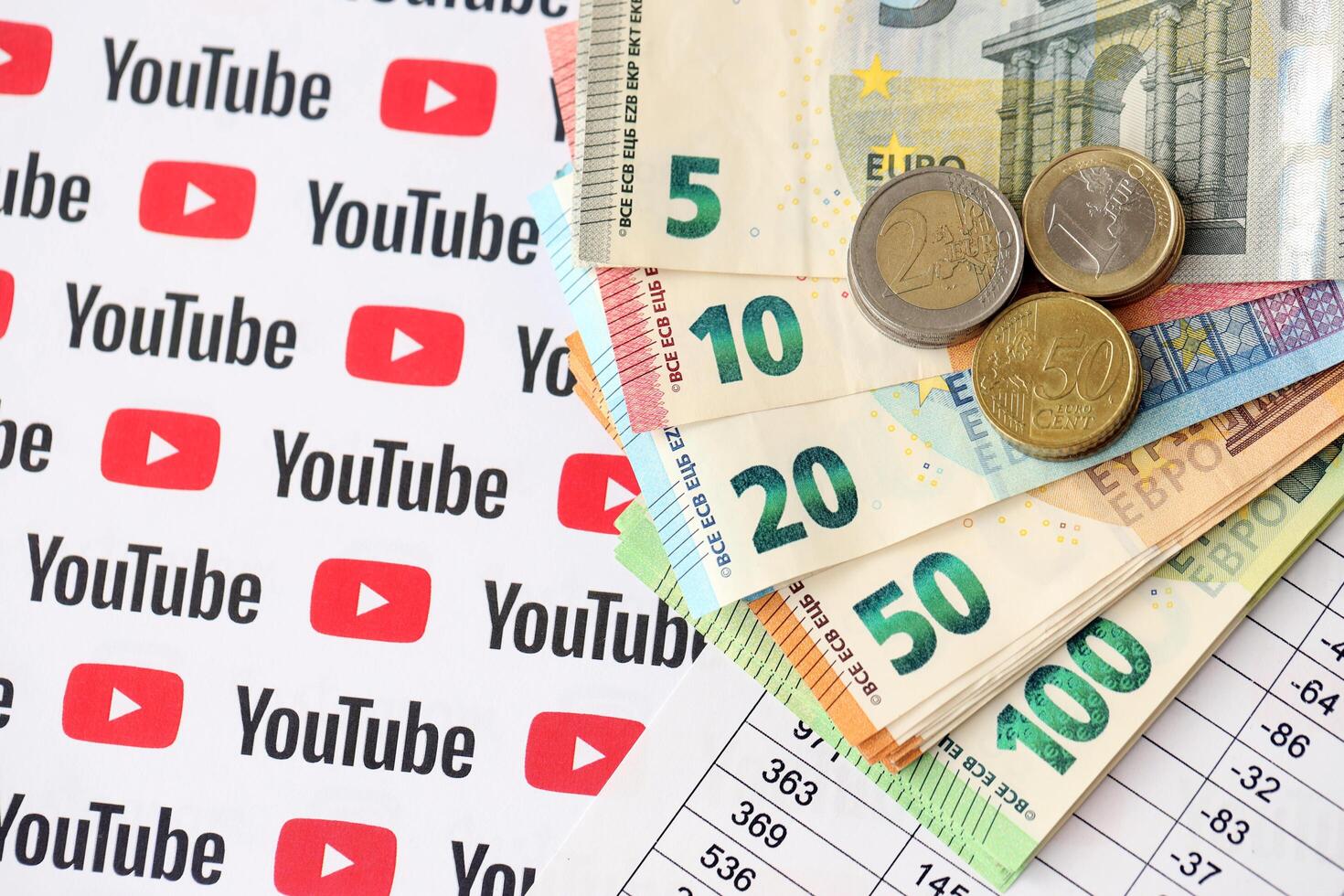 KYIV, UKRAINE - APRIL 20, 2024 YouTube logo and many euro money bills. Symbol of famous social network platform and european currency banknotes photo