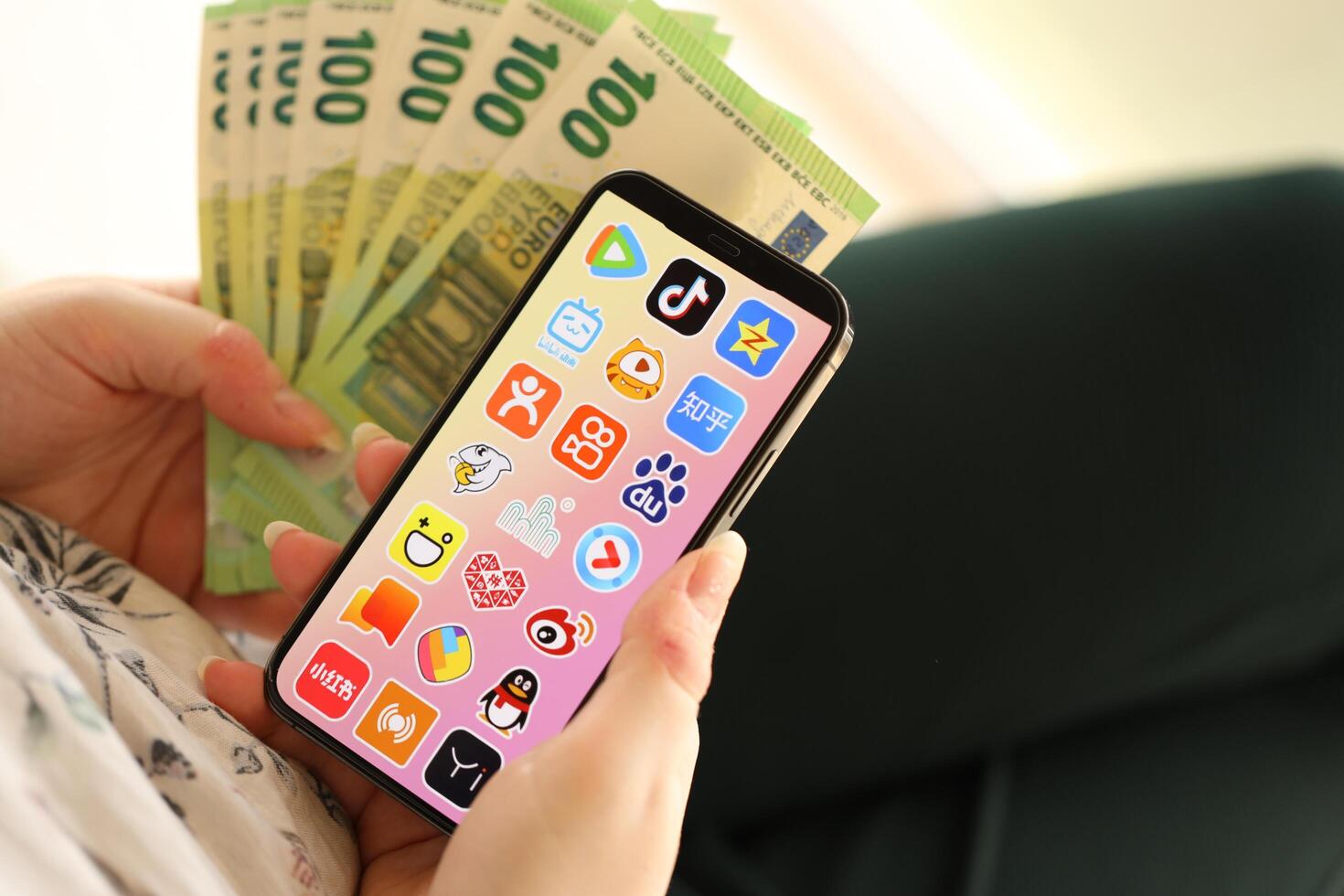 KYIV, UKRAINE - APRIL 1, 2024 Asian apps icon on smartphone screen and money in female hand photo