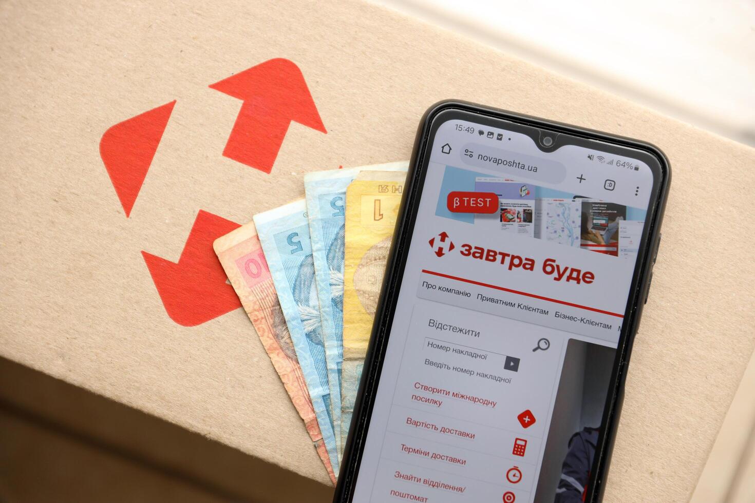 KYIV, UKRAINE - APRIL 20, 2024 Nova Poshta Logotype on cardboard box and website on smartphone screen. Nova Poshta is best ukrainian postal service company photo