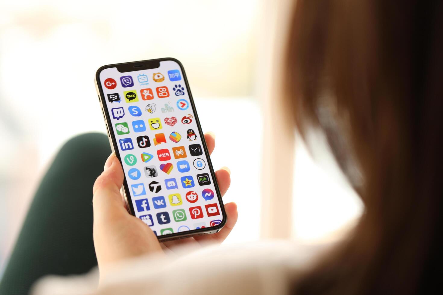 KYIV, UKRAINE - APRIL 1, 2024 Many apps icon on smartphone screen in young female hands photo