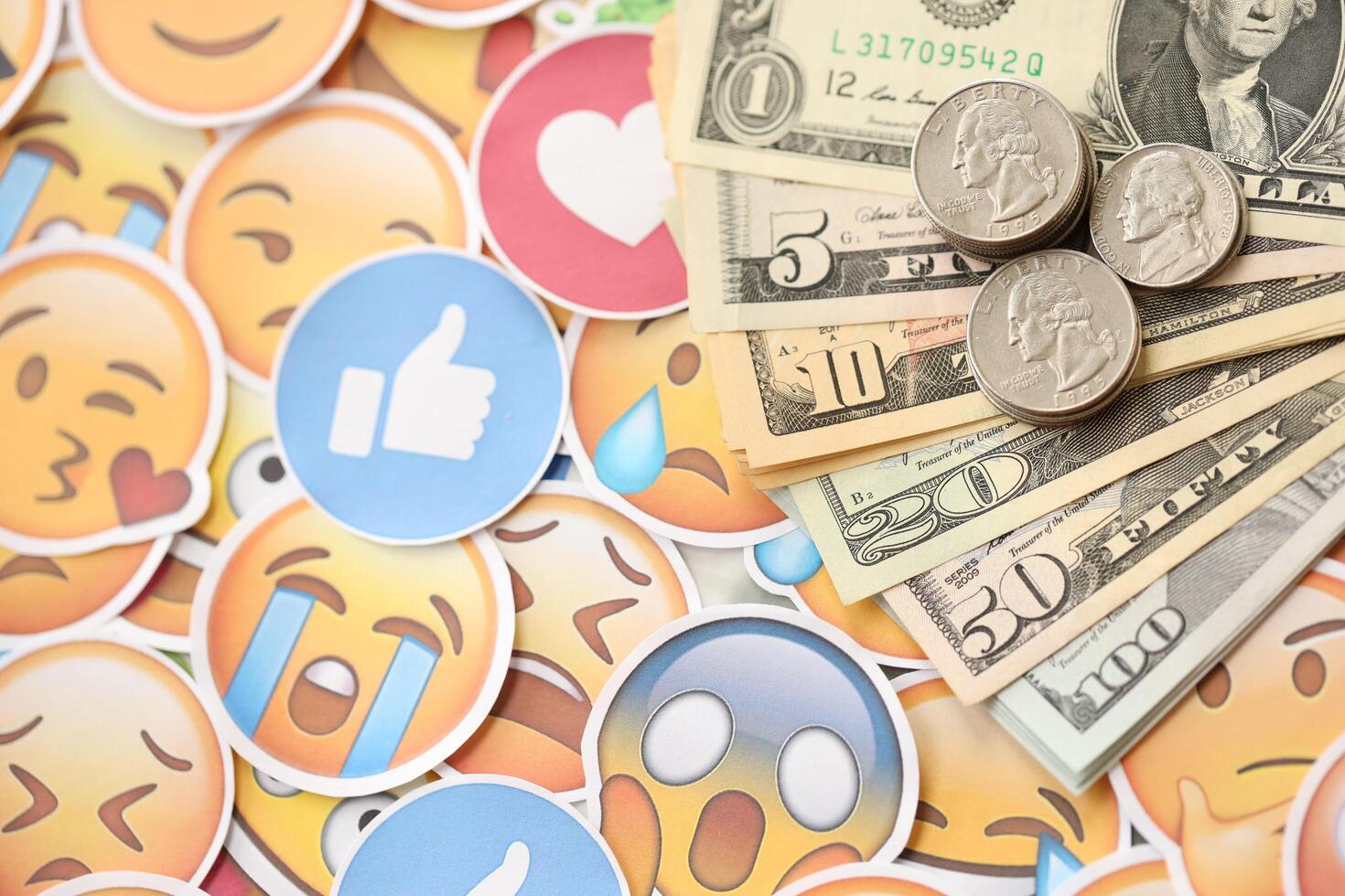 KYIV, UKRAINE - APRIL 20, 2024 USD dollars money and large set of stickers with Emoji yellow faces. The concept of smm, smo paid service for boost in social media photo