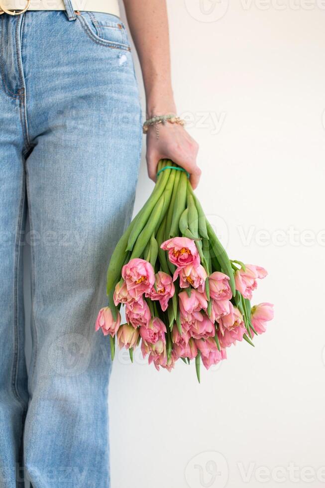 Close-up of pink tulips held by woman in jeans. Springtime and Mother's Day concept photo