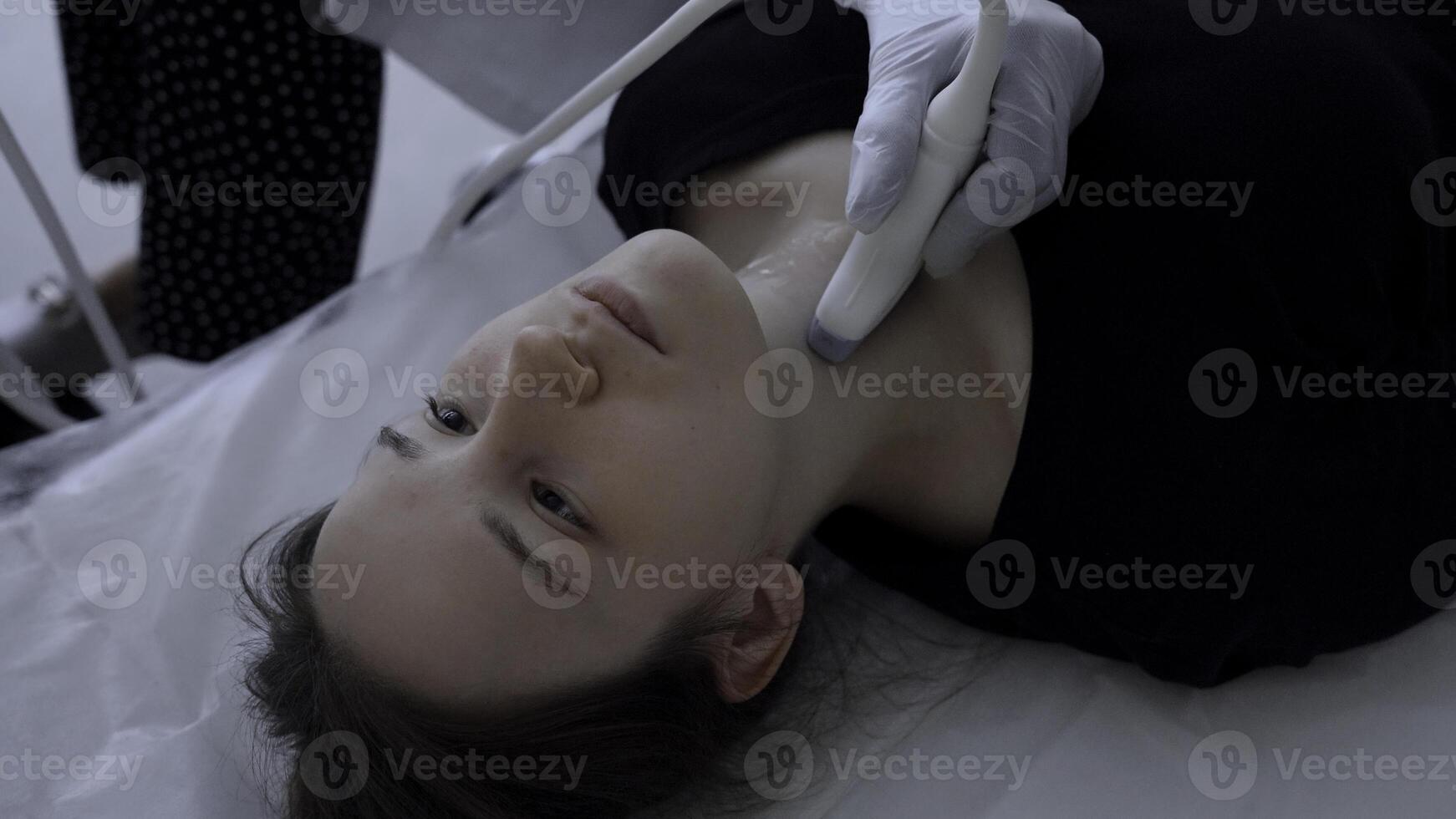 Ultrasound machine doctor conducts examination of thyroid gland of a young woman. Clip. Concept of medicine and health care. photo