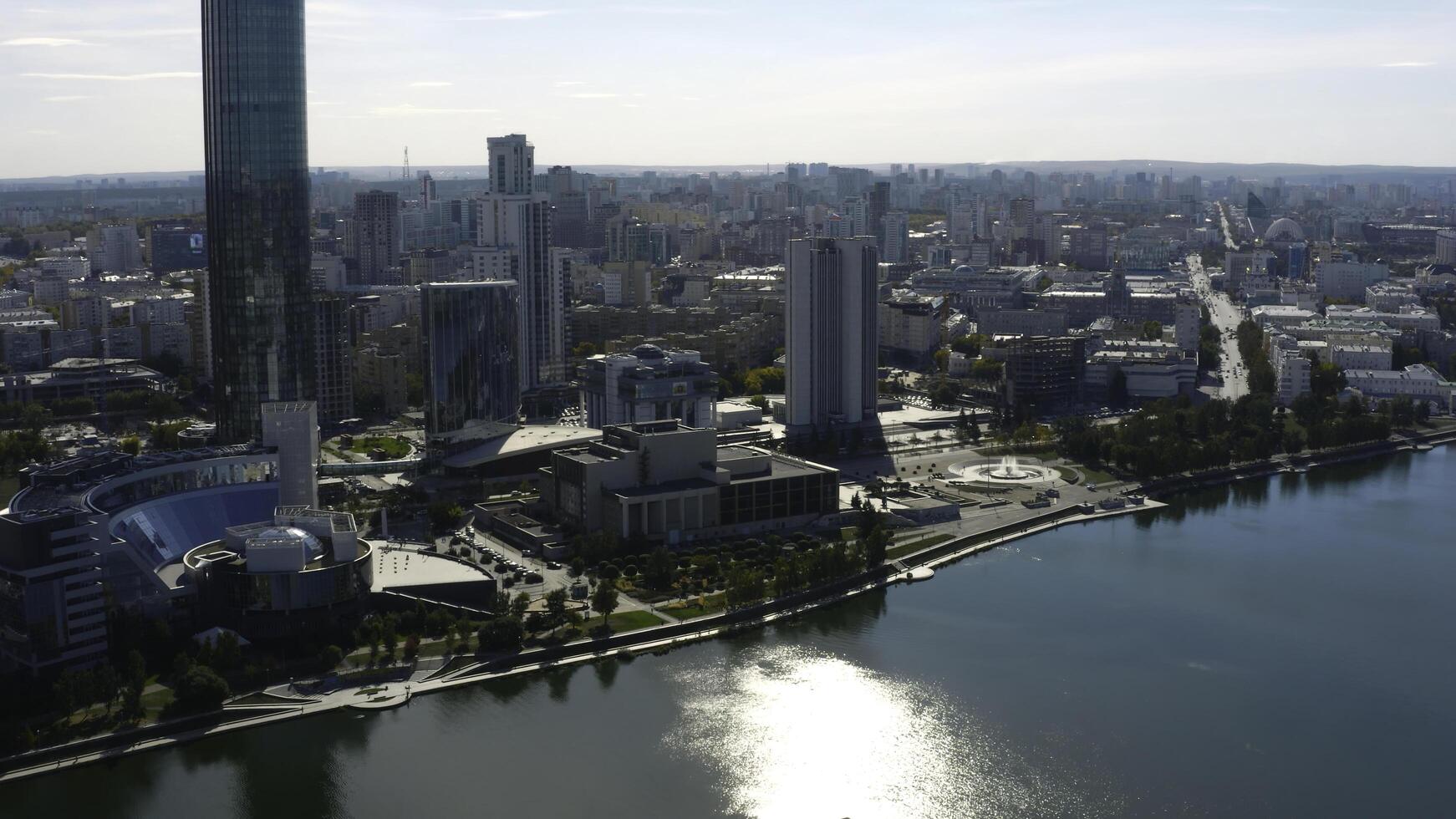 Top view of modern city with river on sunny summer day. Stock footage. High-rise buildings with modern glass buildings of modern city on river. Beautiful modern city with high-rise buildings and river photo