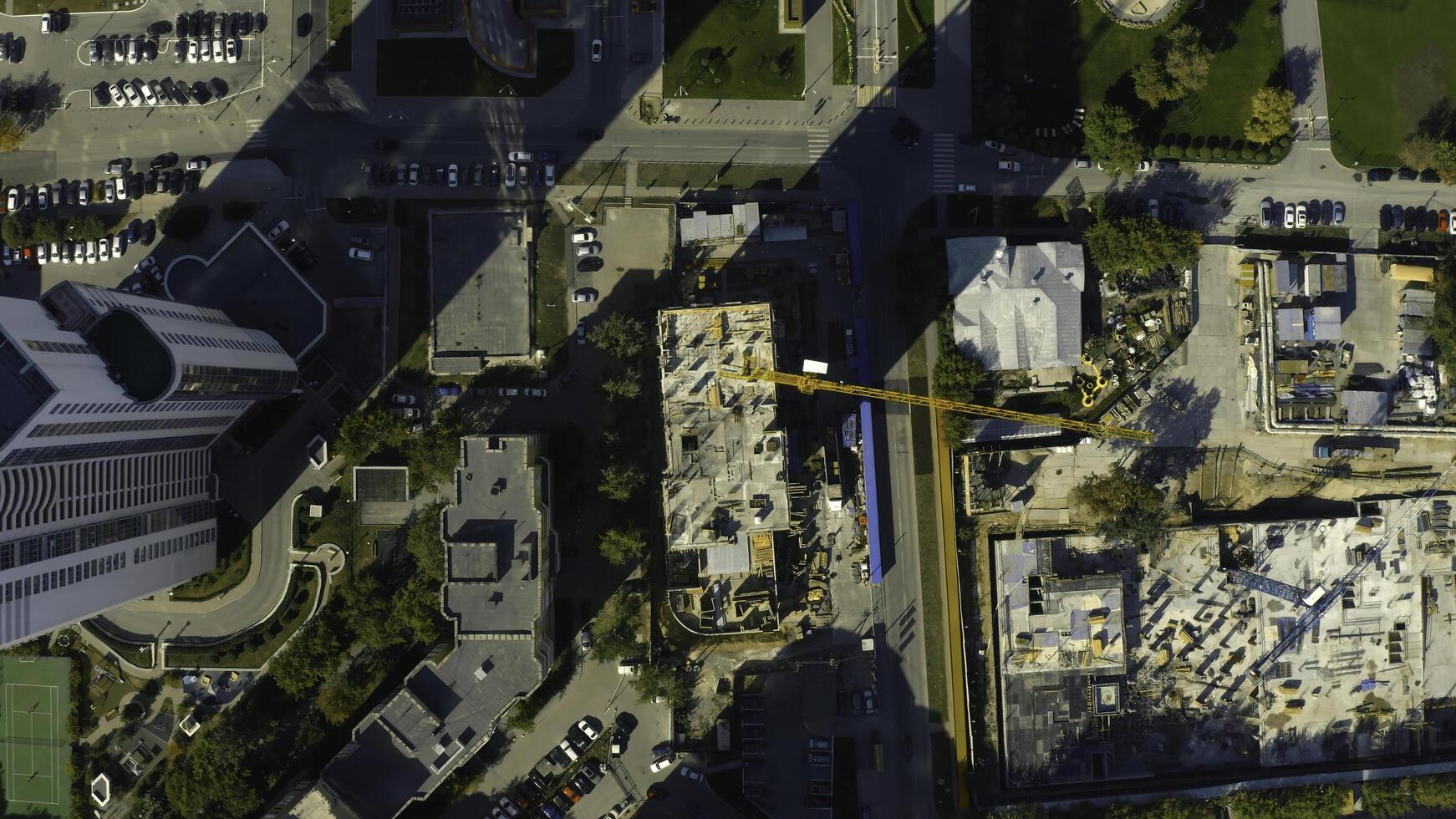 Vertical top view of construction crane in city. Stock footage. Building under construction in center of modern city on sunny summer day. Construction crane in city center photo