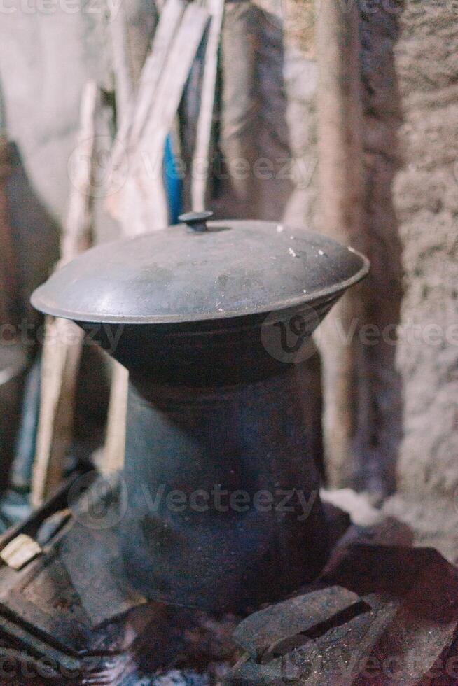 Traditional rice cooker on a wood-burning stove, capturing a rustic cooking method with flames from firewood photo