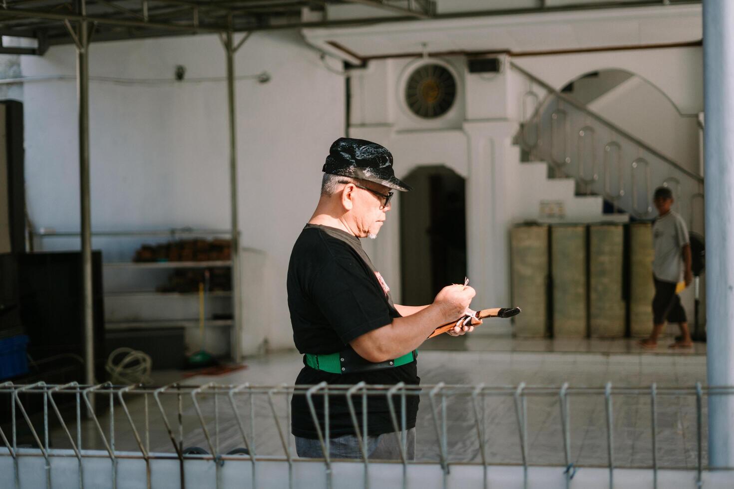 Bogor, Juni 17 2024. A man checks notes on sacrificial goats in a mosque yard celebrating Eid al-Adha. photo