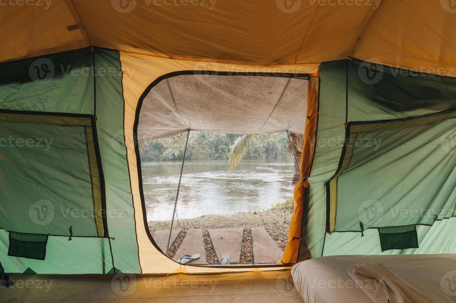 Inside of large comfortable camping tent on campground in the tropical forest by riverside on vacation photo