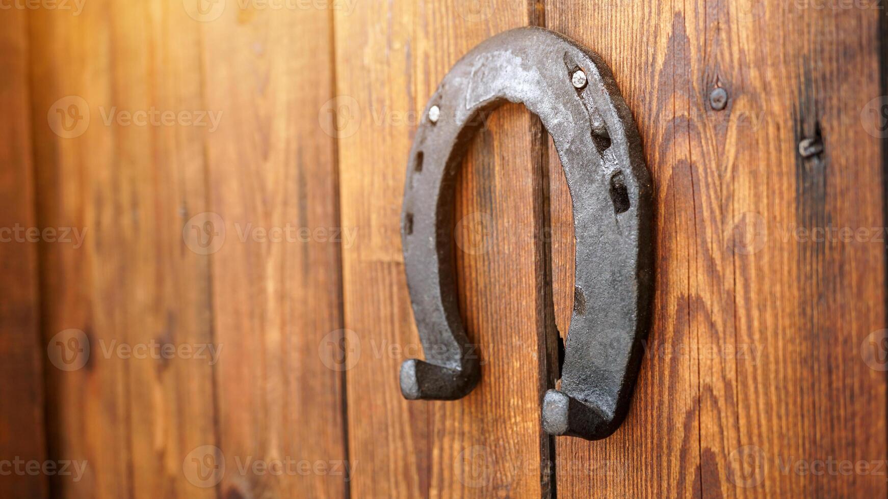 A horseshoe for good luck hanging on a wooden door. Symbol for luck and fortune. An iron lucky horseshoe - a talisman superstition for luck. photo
