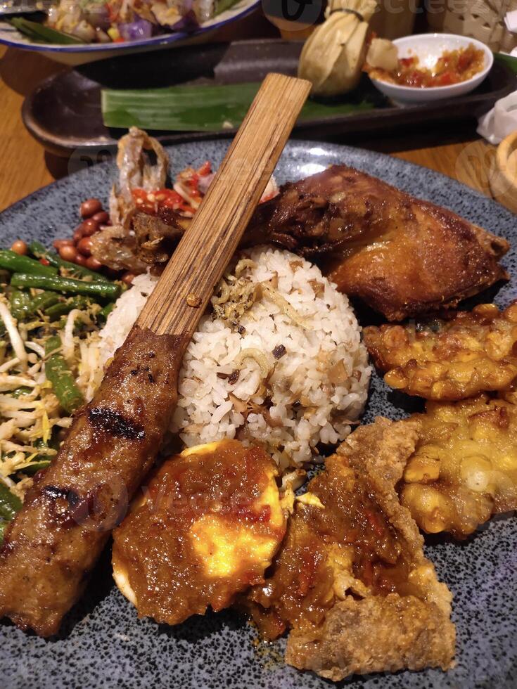 Nasi Goreng Kecombrang or Kecombrang fried rice filled with Lilit satay, egg and fried chicken. Delicious dishes typical of Bali, Indonesia. photo