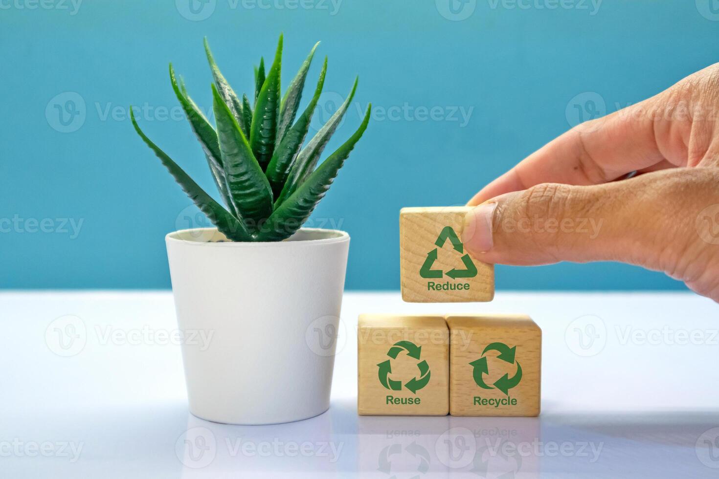 Hand holding wooden blocks with reduce, reuse, recycle symbol. Environmental concept. photo