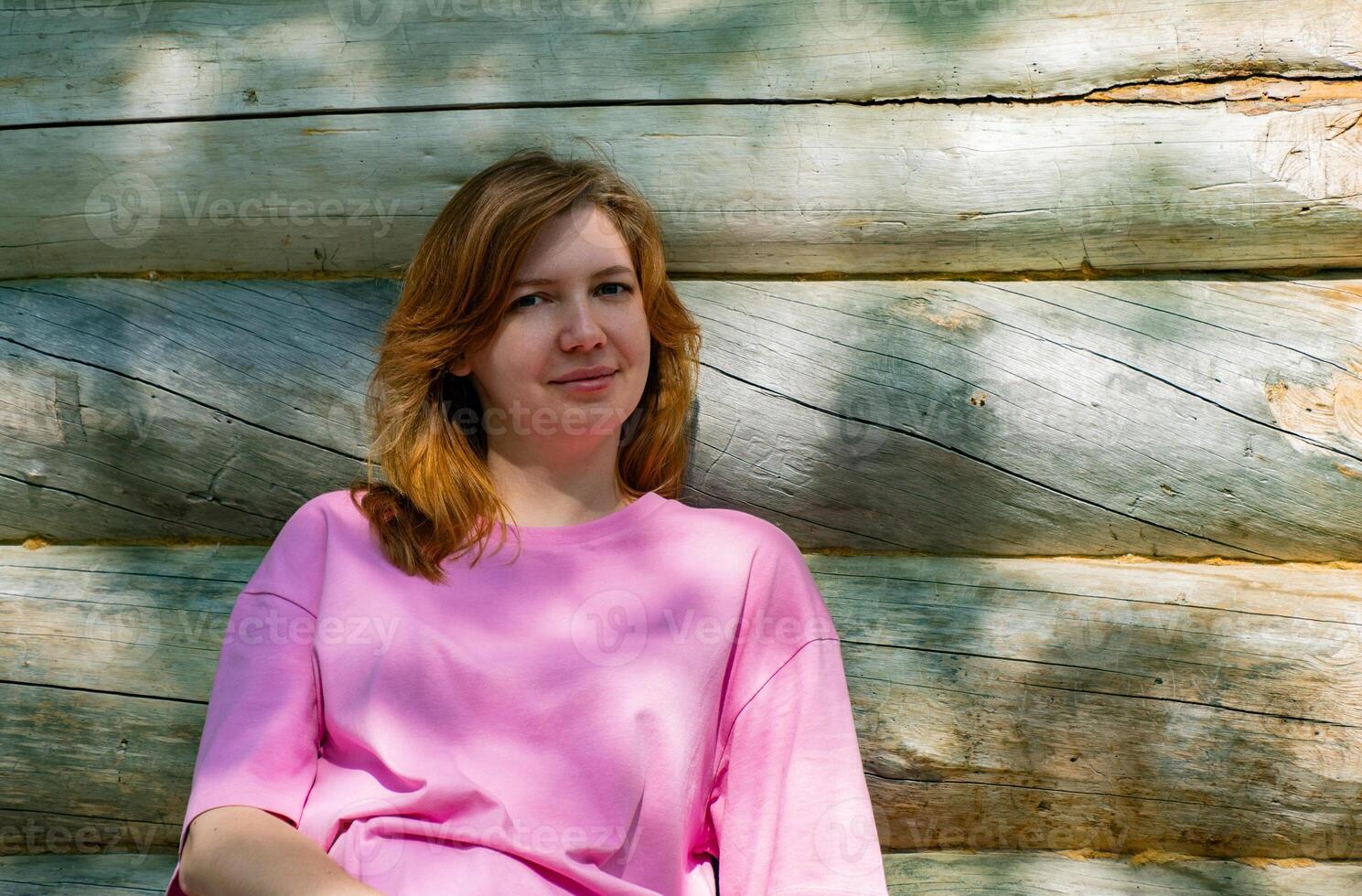 Woman Sitting by Rustic Cabin in Sunny Forest photo
