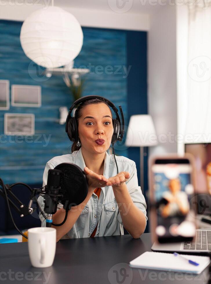 Blogger creator giving blowing kisses while recording talk show podcast. Social media influencer making professional content with modern equipment and digital web internet streaming station photo