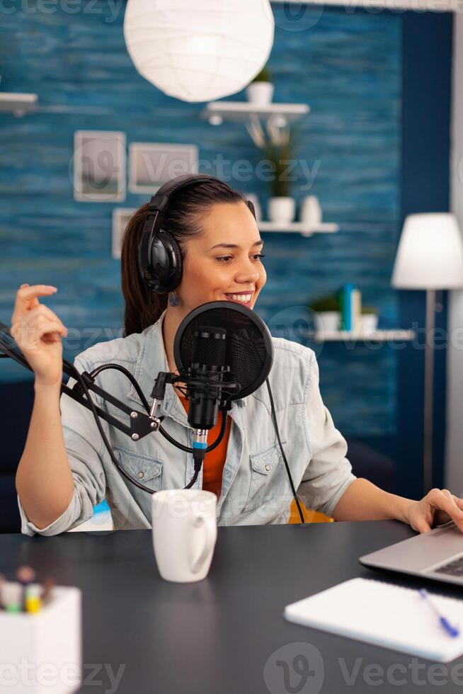 Vlogger looking at laptop while asking her audience to subscribe on her youtube channel. Digital influcencer recording talk show using modern equipment in home studio podcast photo