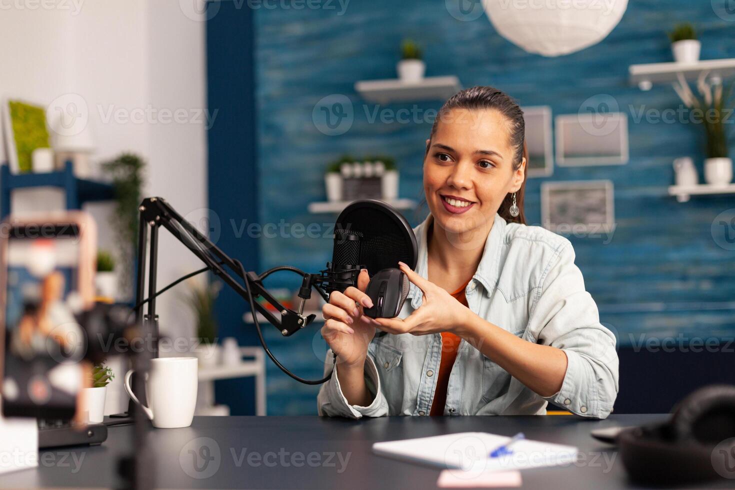 Influencer blogger smiling at camera while recording mouse review for followers. New media star on social media making with professional equipment for online internet podcast show. photo