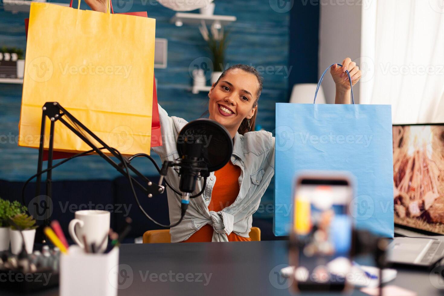 Podcast from social media vlogger with big bags gifts in home studio using professional microphone. Creative content creator influencer recording online giveaway talk show for subscribers audience photo