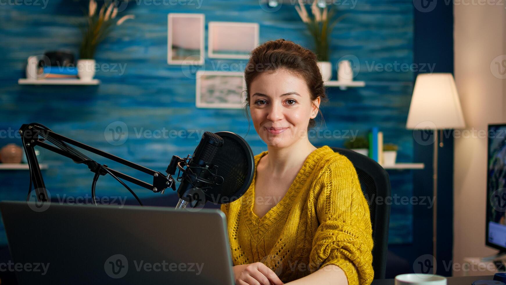 Portrait of vlogger looking at camera and smiling before starting live vlog, recording podcast. On-air online production internet broadcast show host streaming blog content from studio photo