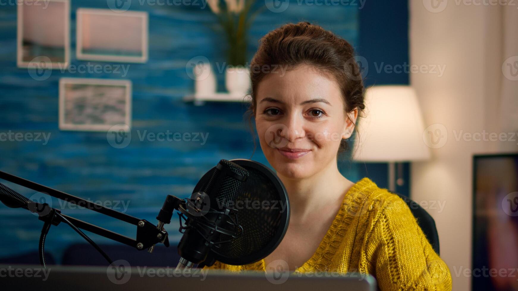 Social media influencer smiling at camera sitting in home studio ready for streaming new podcast. On-air online production internet broadcast show host streaming live content record digital blog photo