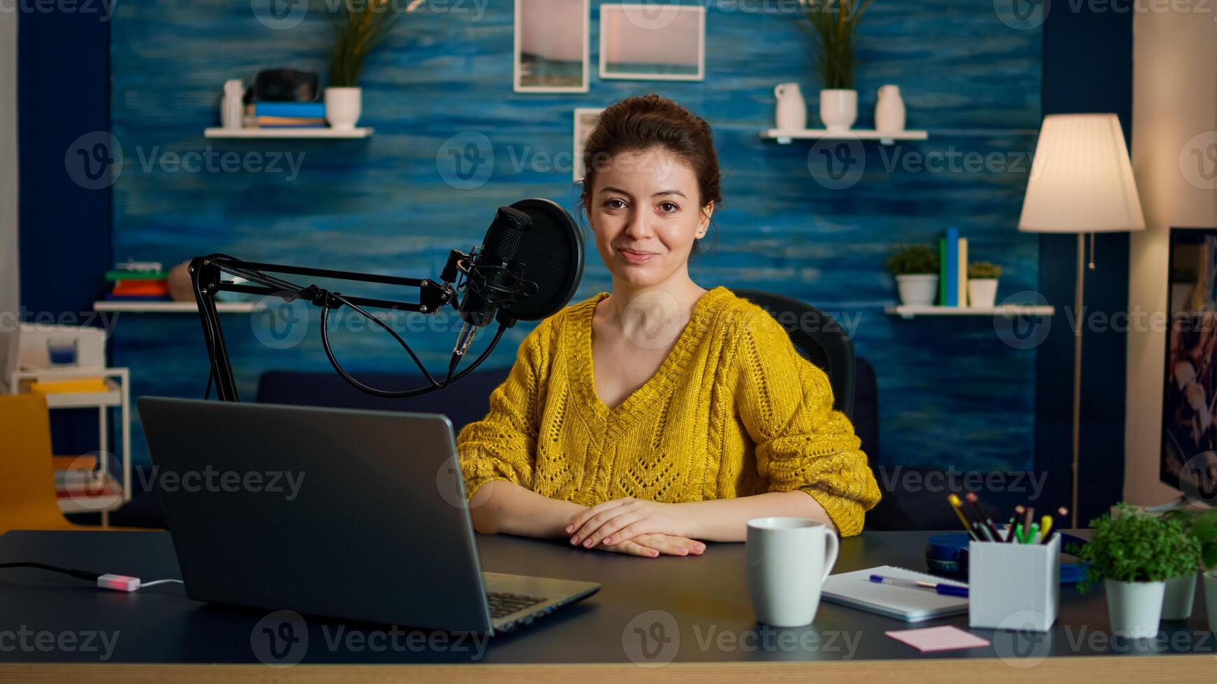 Portrait of young vlogger working in cozy studio, smiling at camera ready to start new podcast show. On-air online production internet broadcast show host streaming web content record digital blog photo