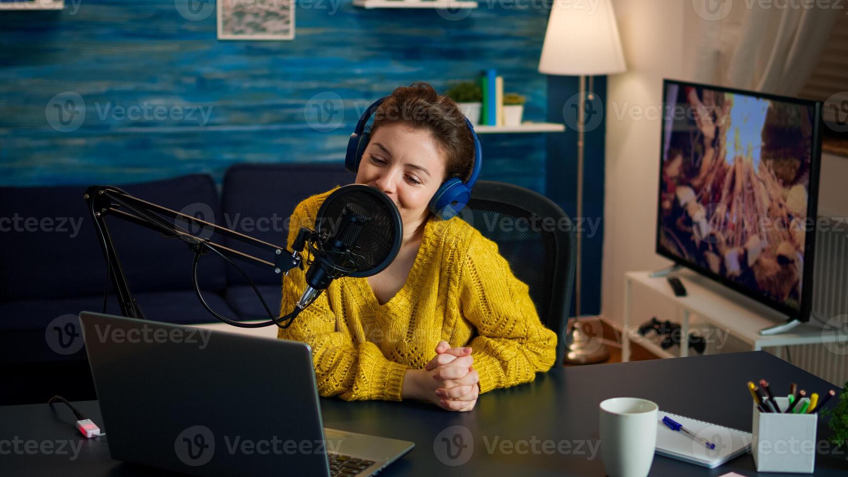Influencer positioning microphone and answering at emails wearing headphones during broadcast in home studio. Creative online show On-air production internet podcast host streaming live content photo