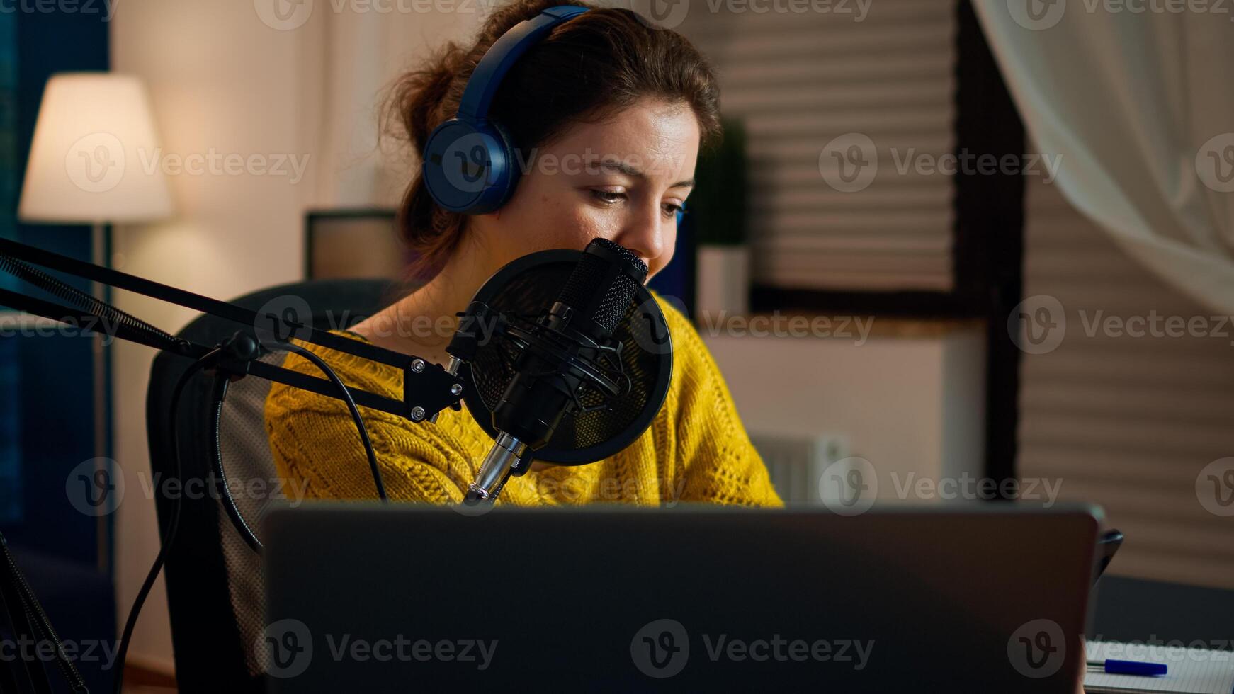 Happy blogger reading messages of fans using smartphone sitting in home podcast studio during livestreaming, recording. Online show On-air production internet broadcast host streaming live content photo