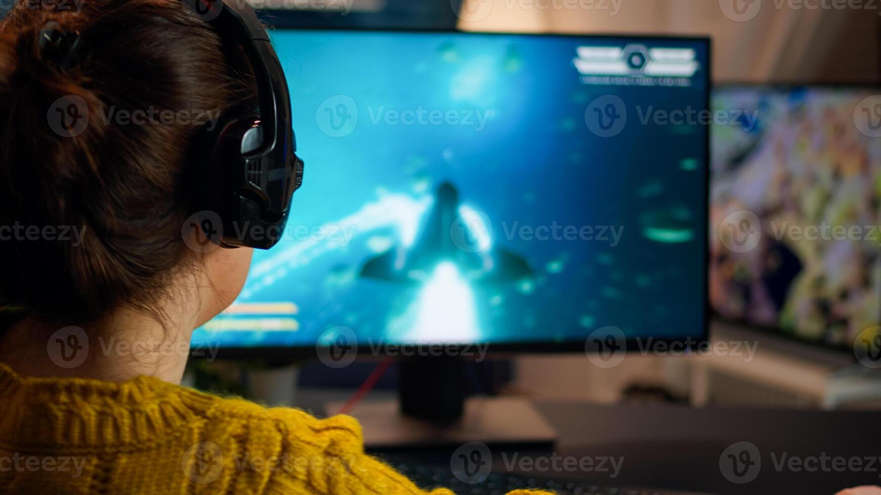 Back view of professional online gamer woman playing shooter game. Pro esport team player streamer playing gaming tournament on powerful RGB computer, using modern streaming technology photo