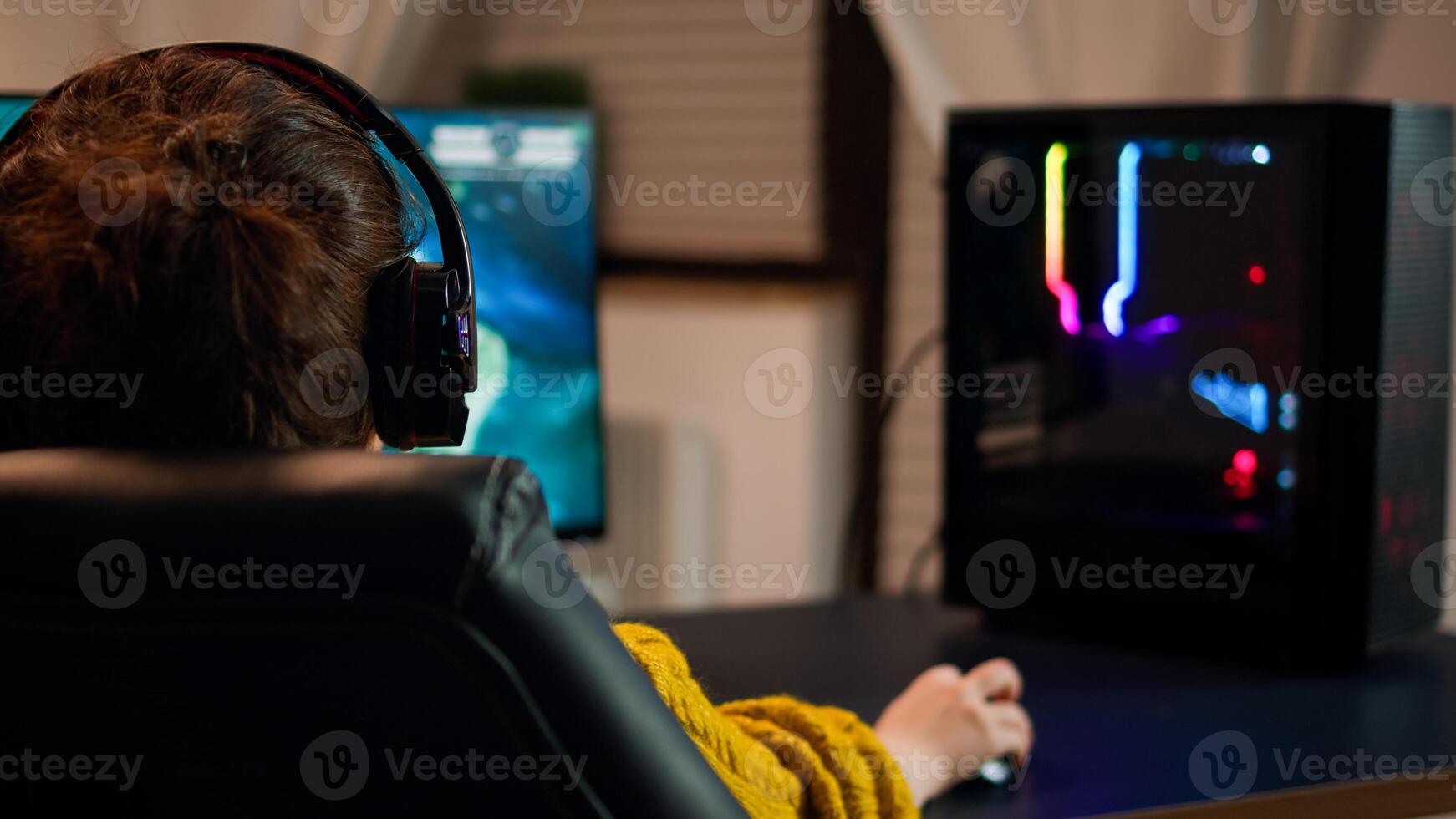 Back view shot of professional gamer playing in first-person shooter online game on computer. Virtual championship in cyberspace, esports player performing on pc during gaming tournament. photo