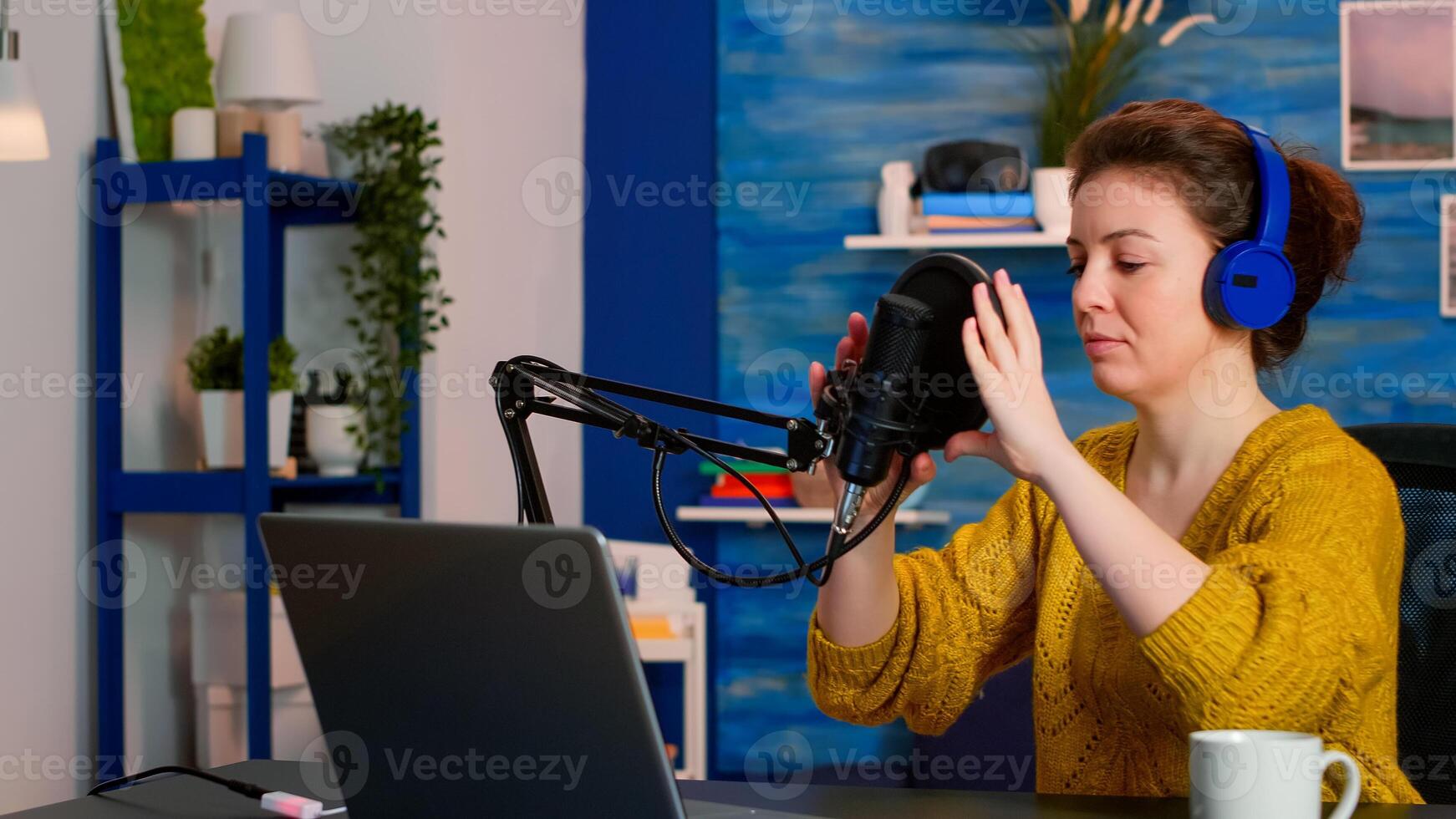 Creative influencer with headphones ready to speak during live on social media recording vlog. On-air online production internet broadcast show host streaming podcast content from studio photo