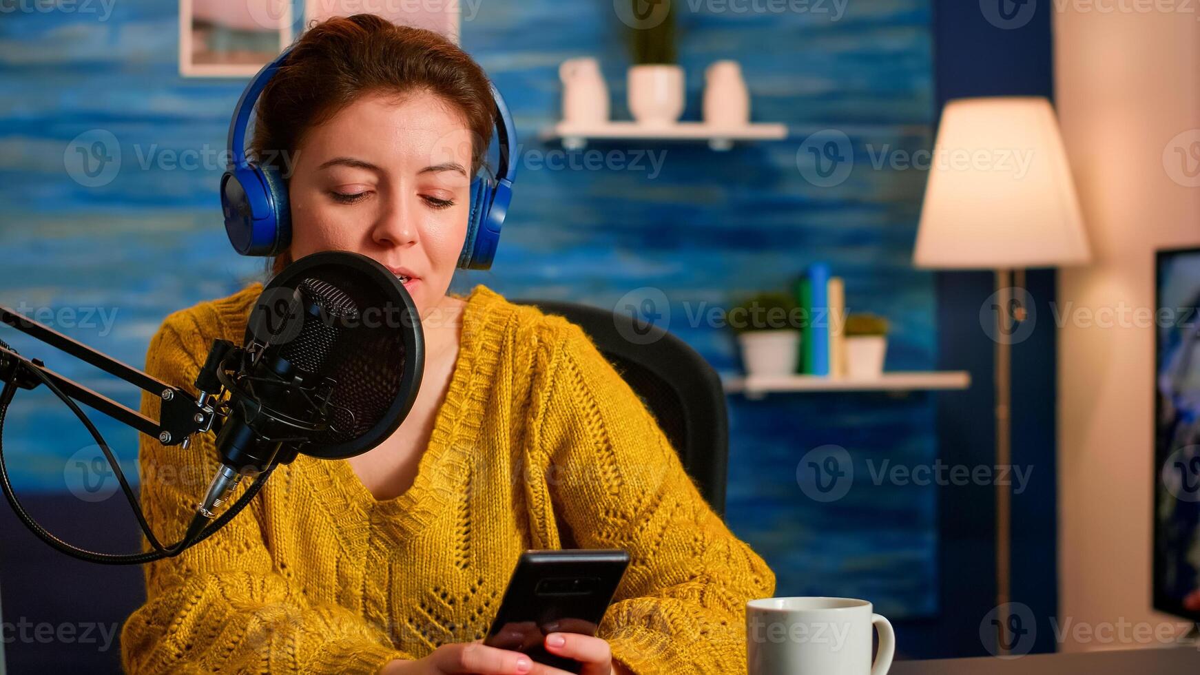 Famous blogger with headphones streaming from home studio texting wih followers during recording vlog. On-air online production internet broadcast show host livestreaming content for social media photo
