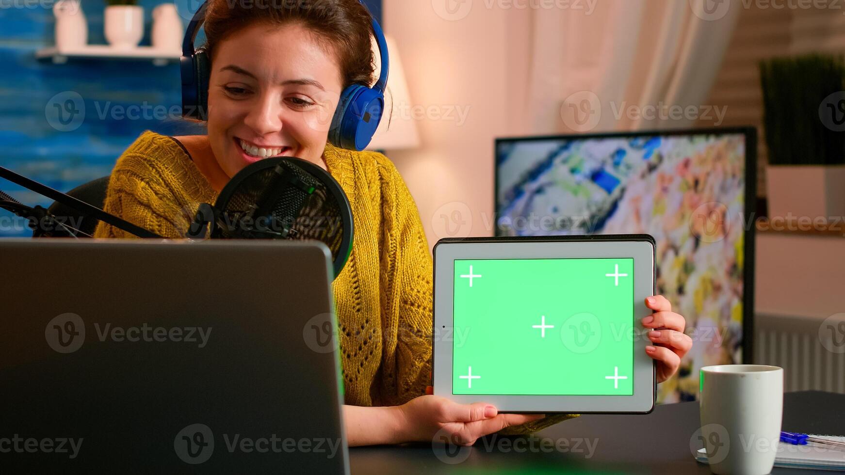 Blogger talking into microphone holding notepad with green screen during entertainment podcast. On-air production internet broadcast host streaming live content using chroma key, mockup display photo