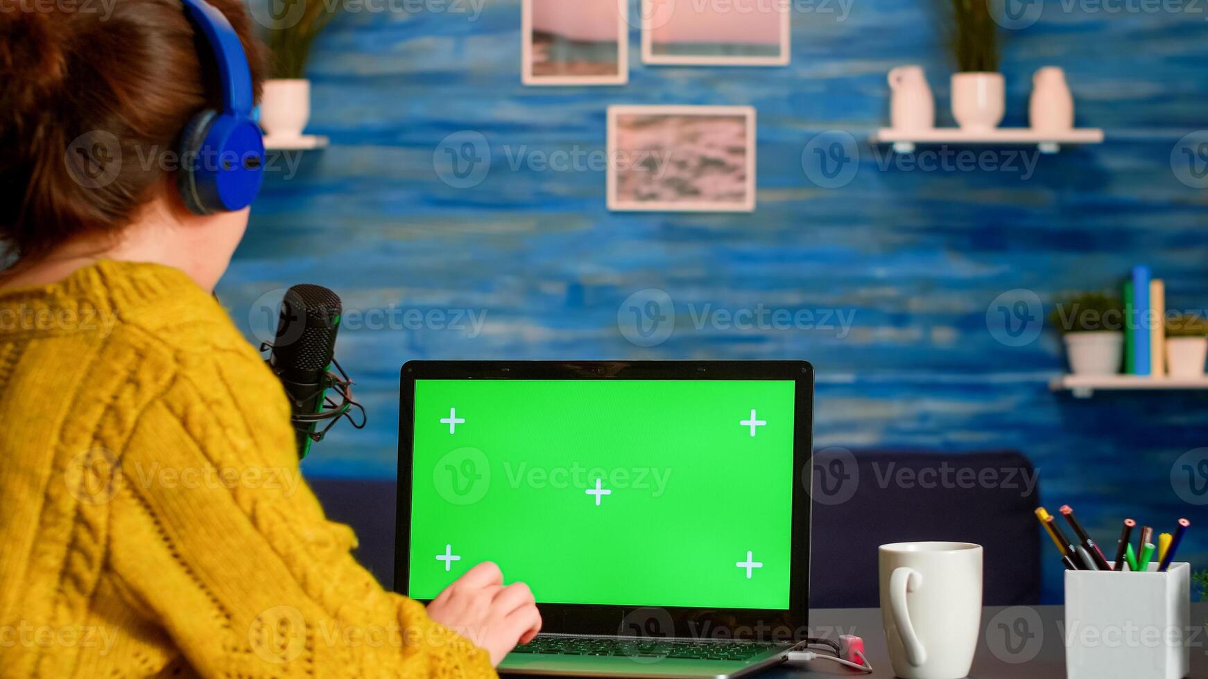 Vlogger reading at laptop with chroma key desktop during livestreaming from home studio. On-air production internet broadcast host streaming live content using mochup, green screen, izolated desktop photo