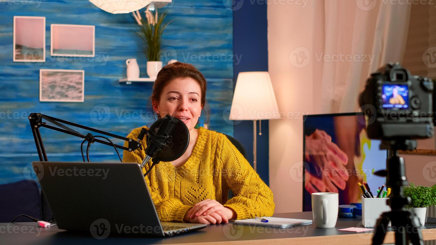 Blogger recording vlog on digital camera sit in living room studio, shooting social media blog on camcorder talking with fans. On-air online production internet broadcast show host streaming photo