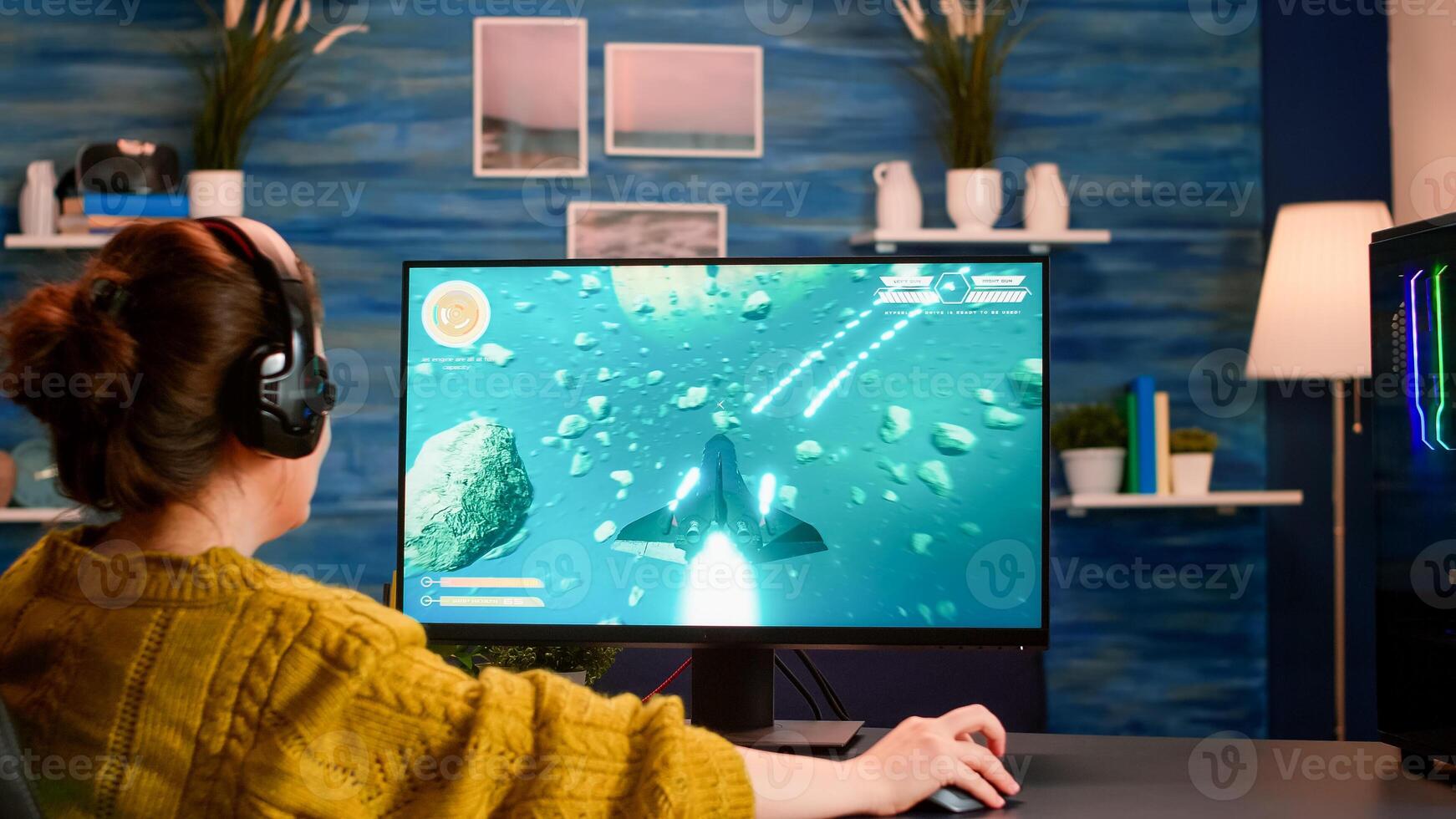 Over the shoulder woman gamer playing online professional shooter game on computer at home late at night. Professional player testing online games on pc with modern technology network wireless. photo