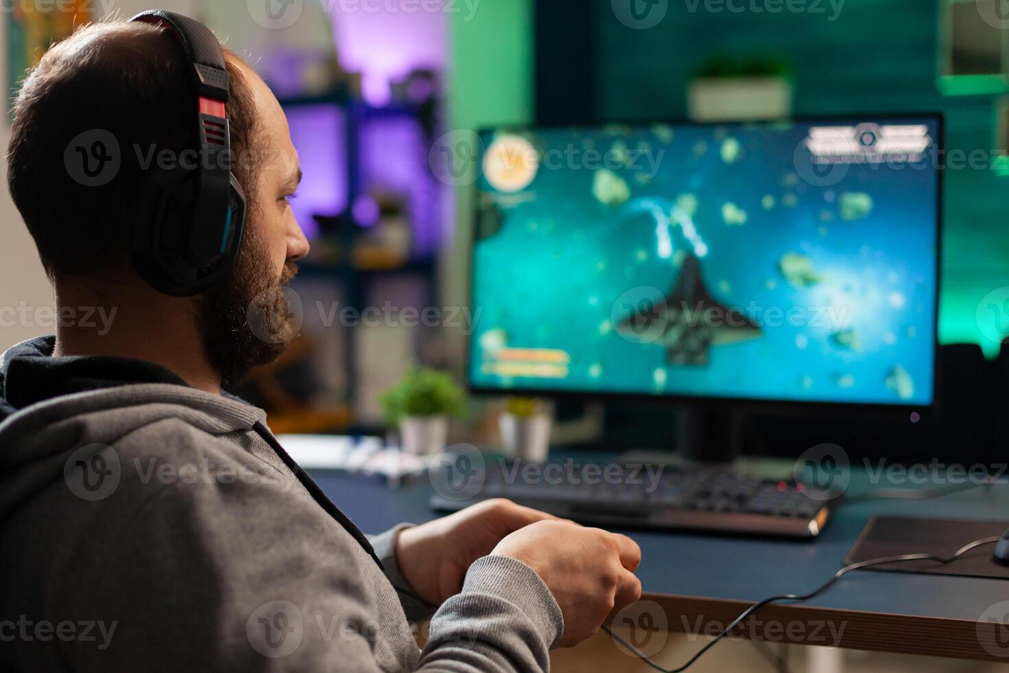 Videogamer playing graphics cyberspace sitting on gaming chair using technology network wireless. Man streaming viral videogames for fun using headphones and joystick for online championship photo