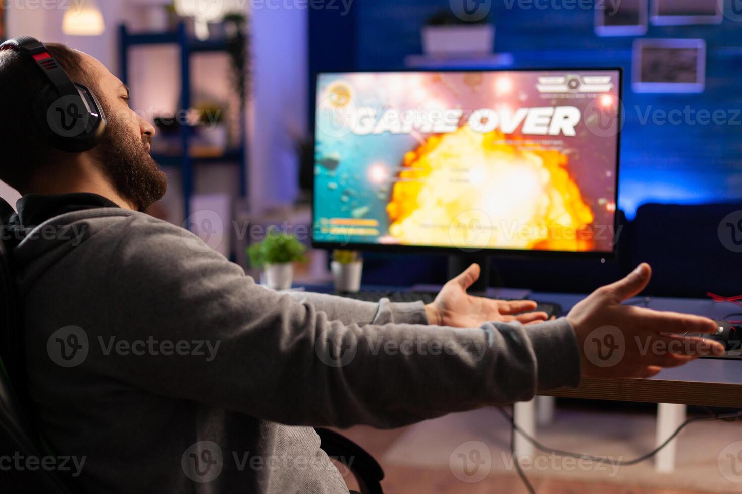 Game over for gamer playing videogames on computer during night time in gaming room home. Defeated man with headphones streaming online cyber performing through tournament photo