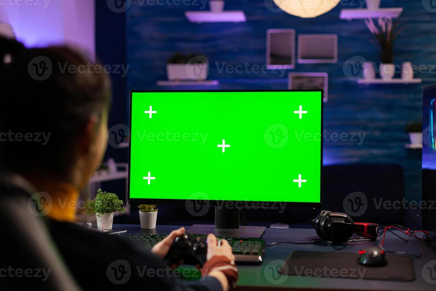 Pro gamer playing virtual videogames on professional powerful computer with green screen display. Cyber Player using pc with mock up chroma isolated desktop streaming shooter games wearing headset photo