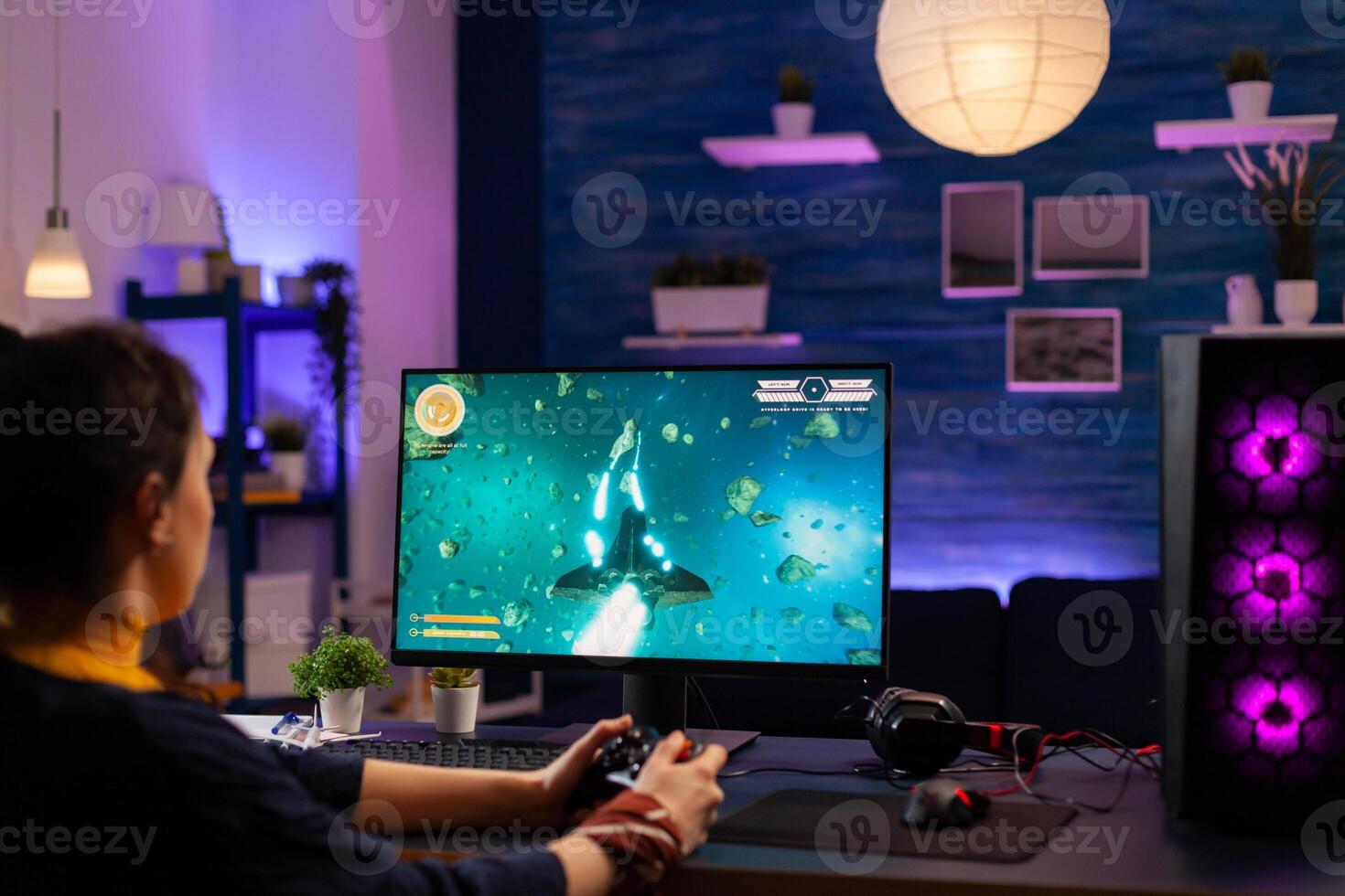 Concentrated player sitting on gaming desk late at night using wireless controller playing space shooter. Virtual streaming cyber performing live tournament using professional equipment photo