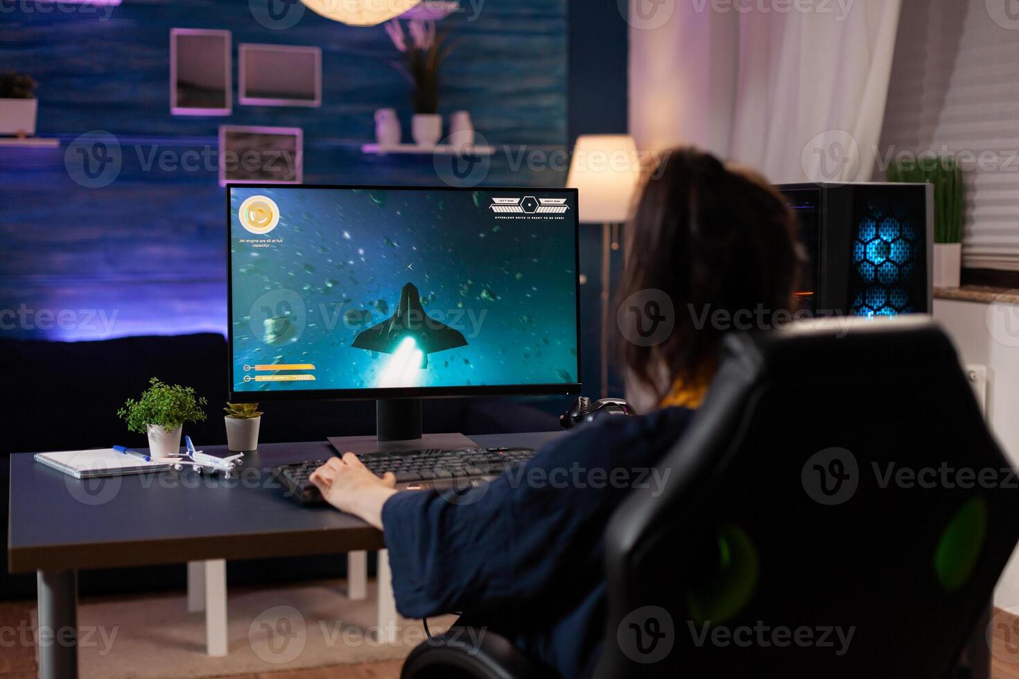 Focused player sitting on gaming chair in home studio and playing online videogames using RGB keyword. Professional pro player streaming online game new graphics using powerful computer photo