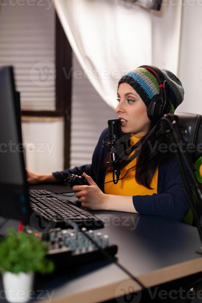 Side view of pro streamer with headphone playing shooter game competition using modern equipment. Player sitting on gaming chair using wireless console and talking with other gamers into microphone. photo