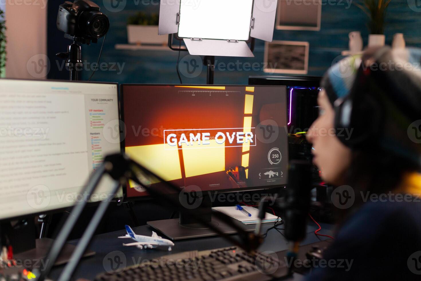 Game over for streamer talking into microphone with other players via streaming chat wearing headphones. Online cyber performer during gaming tournament using powerful PC with RGB photo