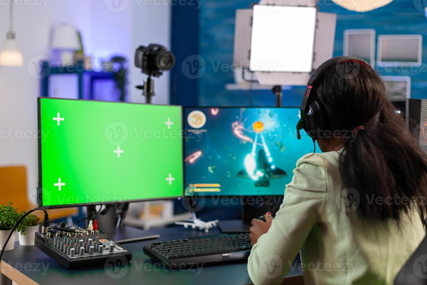 African strategy player streams using computer for e sports with chroma key at night talking with multyplayers. Gamer using pc with greenscreen isolated desktop streaming space shooter games. photo
