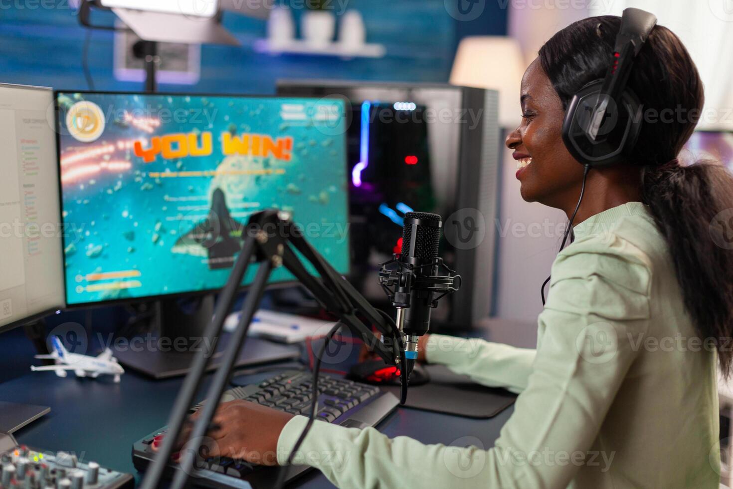 Excited professional african e sports player during game stream of competition after winning. Online streaming cyber performing during games tournament in home with neon lights. photo